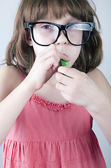 Image showing girl with herd sunglasses blowing a balloon