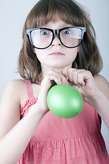 Image showing funny  girl with herd sunglasses blowing a balloon