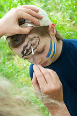 Image showing portrait of a child with his face being painted