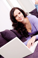 Image showing smiling woman on couch with notebook