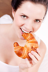Image showing smiling woman eating a croissant