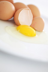 Image showing One broken egg in the foreground on a plate