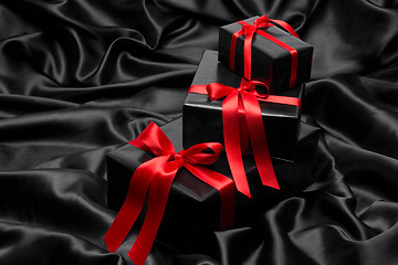 Image showing Black gift boxe with red satin ribbons and bows, over black satin