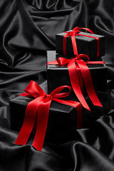 Image showing Black gift boxe with red satin ribbons and bows, over black satin