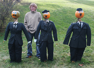 Image showing Man poses with pumpkin people in suits