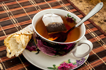 Image showing cup of tea with pastry after dinner