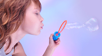 Image showing  girl  blowing soap bubbles against bright background