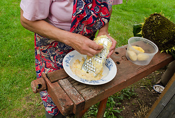 Image showing senior woman grate peel potatoes steel shredder 