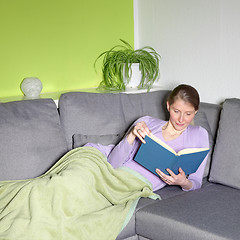 Image showing Woman relaxing reading on a sofa