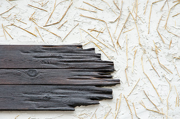 Image showing A background of a wall with black planks, white plaster and stra