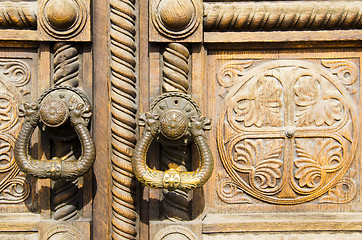 Image showing Two old handles on a wooden door with ornaments