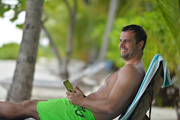 Image showing man ralaxing and use tablet at beach