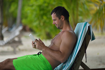 Image showing man ralaxing and use tablet at beach