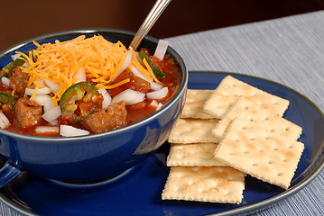 Image showing Bowl of spicey chili and crackers with a spoon