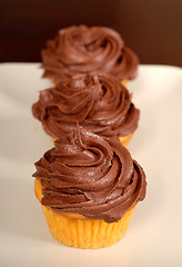 Image showing Three chocolate frosted cupcakes in a row