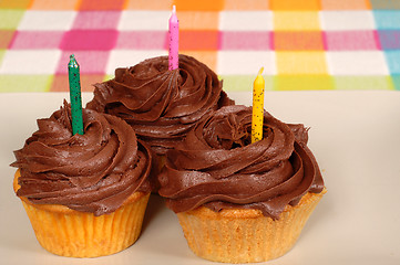 Image showing Three chocolate frosted cupcakes with candles