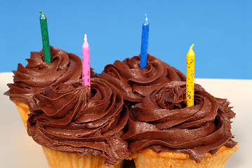 Image showing Four chocolate frosted cupcakes with candles