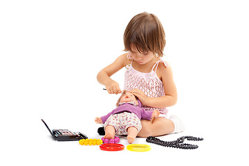 Image showing Beautiful little girl paints cosmetics doll