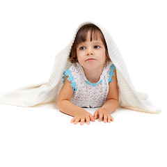 Image showing Thoughtful little girl lying on the floor wrapped in a light bla