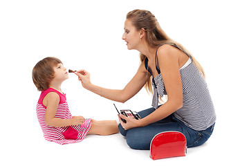 Image showing Young mother paints little girl cosmetics