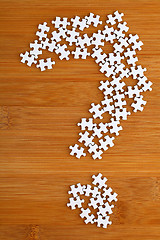 Image showing question mark made by puzzle on wood background