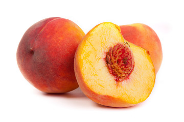 Image showing Three tasty juicy peaches with a half  on a white background