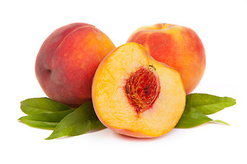 Image showing Three tasty juicy peaches with a half  on a white background