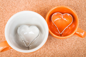 Image showing Ceramic cups with cookies cutter on cork background