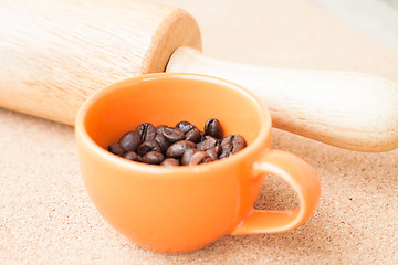 Image showing Cup of roast coffee bean and roller on cork background