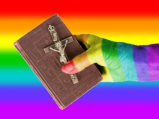 Image showing Old hand (woman) holding a very old bible, rainbow flag