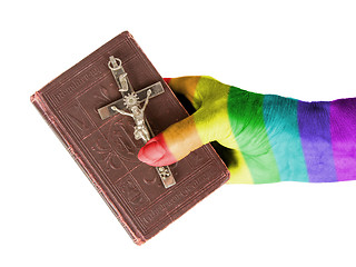 Image showing Old hand (woman) holding a very old bible, rainbow flag