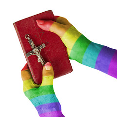 Image showing Old hands holding a very old bible, rainbow flag pattern