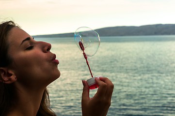 Image showing Young woman blowing bubbles