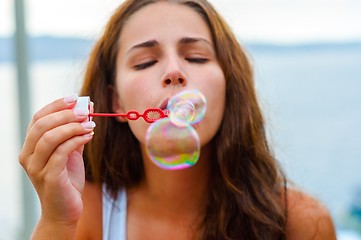 Image showing Young woman blowing bubbles
