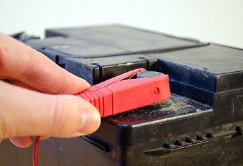 Image showing closeup hand plug car battery red clamp plus 