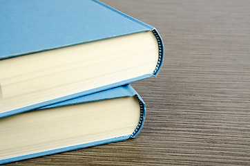 Image showing Two blue books on a table with wooden texture