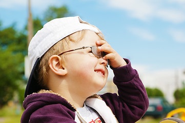 Image showing Little boy in glasses hand covers the eyes from bright sun 