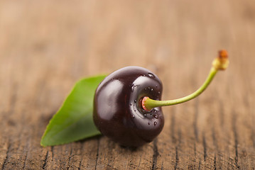 Image showing Red, ripe, juicy cherry and leaf on wooden boards