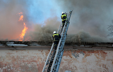 Image showing Firefighters extinguish fire from a high ladder