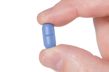 Image showing Hand holding a blue pil