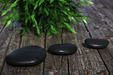 Image showing Three black spa or prayer stones and herbs