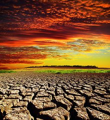 Image showing red dramatic sunset over dry cracked earth