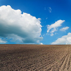 Image showing black ploughed field under blue sky with clouds