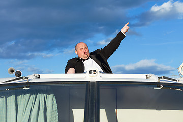 Image showing Overweight man in a tuxedo at the helm of a pleasure boat