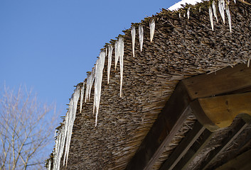 Image showing small icicles retro straw roof background blue sky 