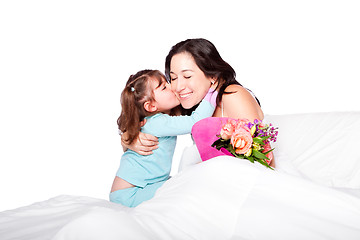 Image showing Child gives flowers and kiss to mom in bed