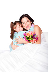 Image showing Child gives flowers to mother in bed