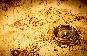 Image showing Vintage compass lies on an ancient world map.