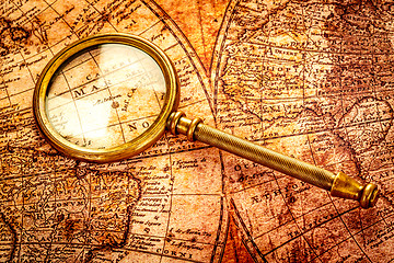 Image showing Vintage magnifying glass lies on an ancient world map