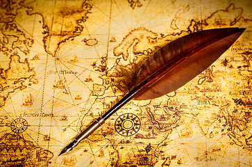 Image showing Vintage goose quill pen lying on an old map.